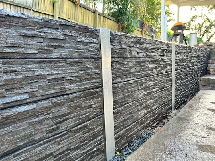 Stacked-stone finish concrete sleeper retaining wall with galvanised steel posts