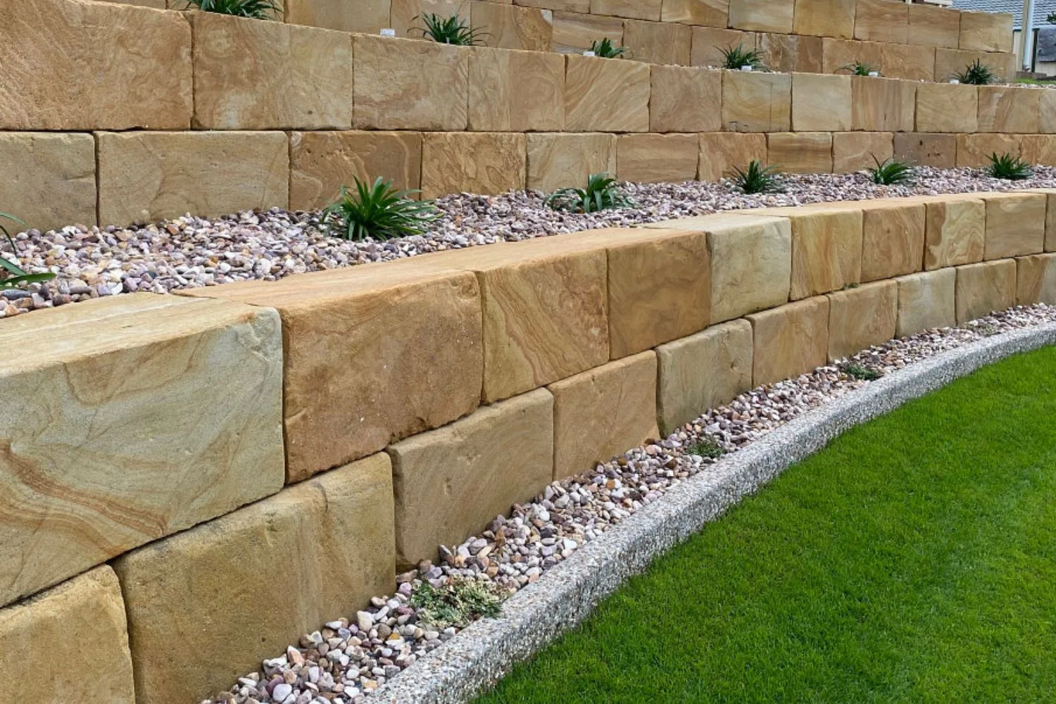Sawn sandstone block retaining wall with a gravel strip and curved concrete edge
